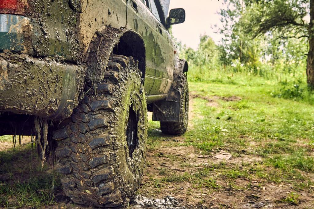 Dirty SUV is standing on the lawn after an off-road race, covered in slush. A beautiful photo of nature and a offroader in a beautiful meadow