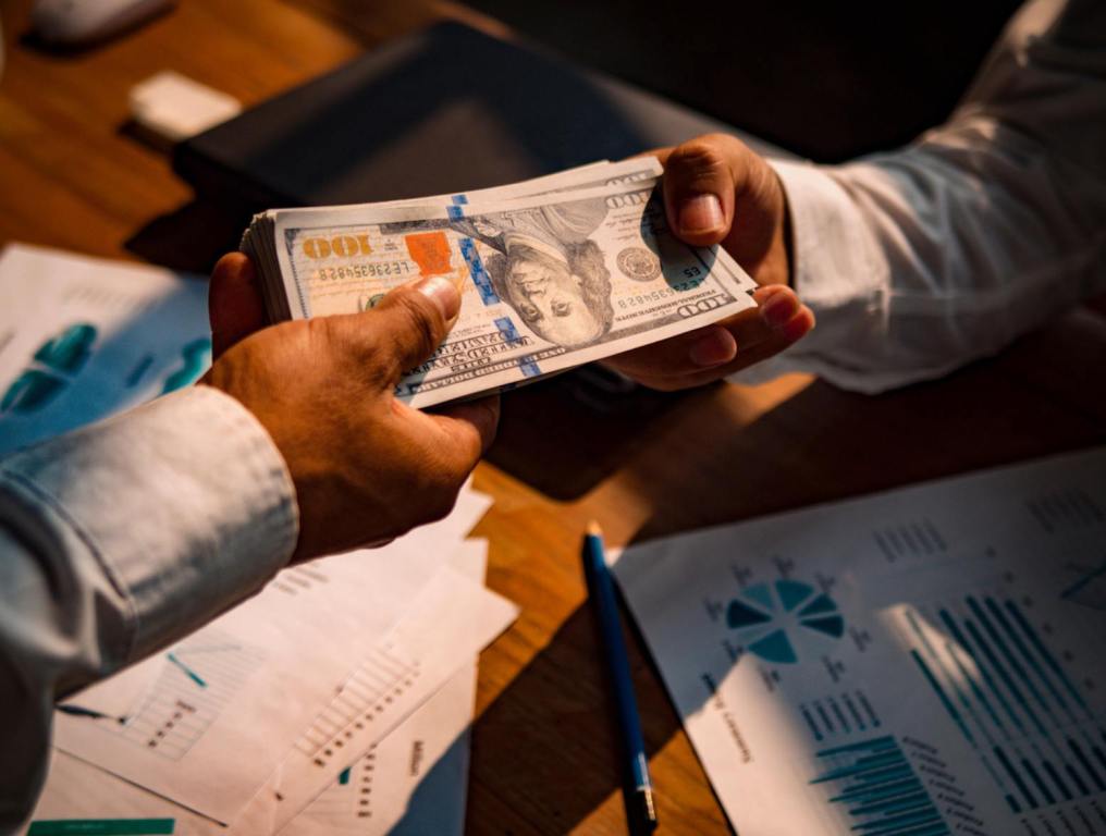 Man handing employee stack of $100 bills