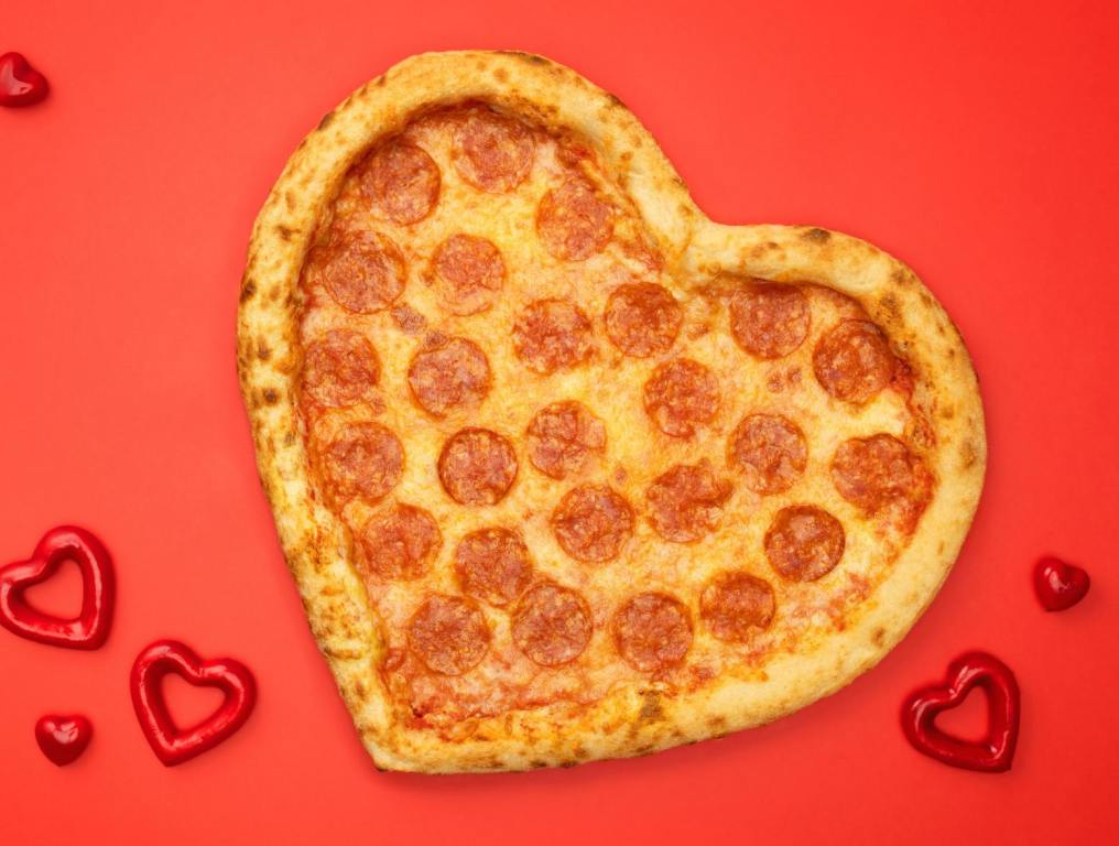 Heart-shaped pizza with red background and balloon hearts