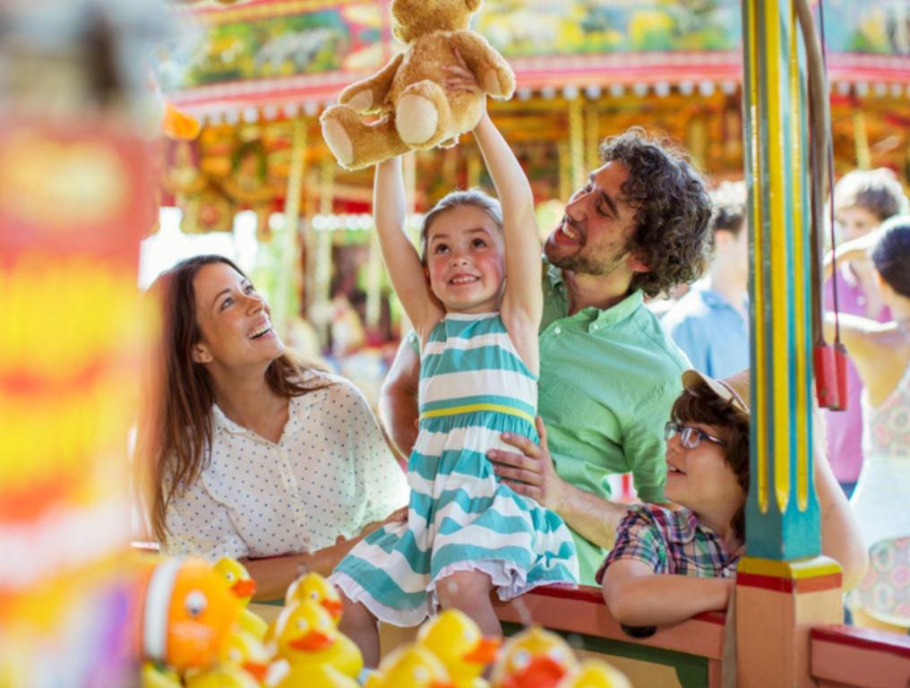 Girl holding teddy bear as trophy in fishing game in amusement theme park