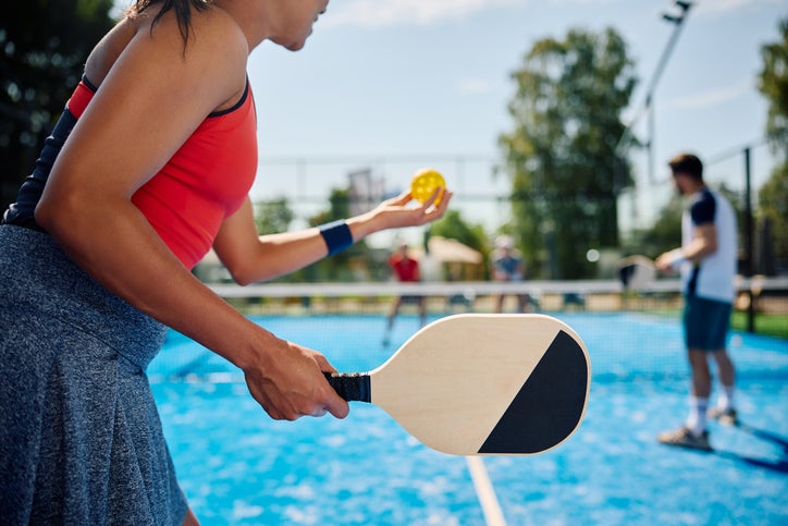 Female about to serve a pickleball at a pop-up pickleball court. With friends on a sunny day.