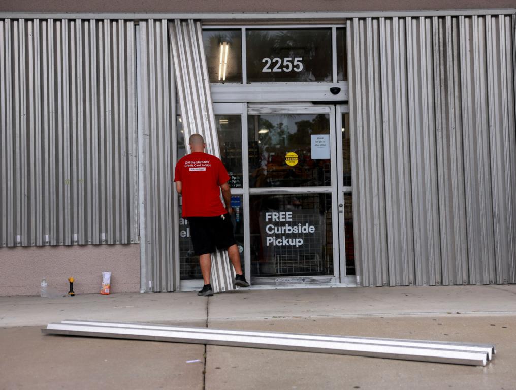 Jason Ross puts hurricane shutters over the windows of the business he manages before the arrival of Hurricane Milton on October 08, 2024 in Naples, Florida.